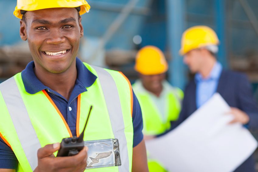 happy african american industrial worker with walkie talkie on site