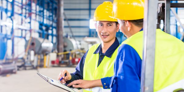 Worker and forklift driver in industrial factory