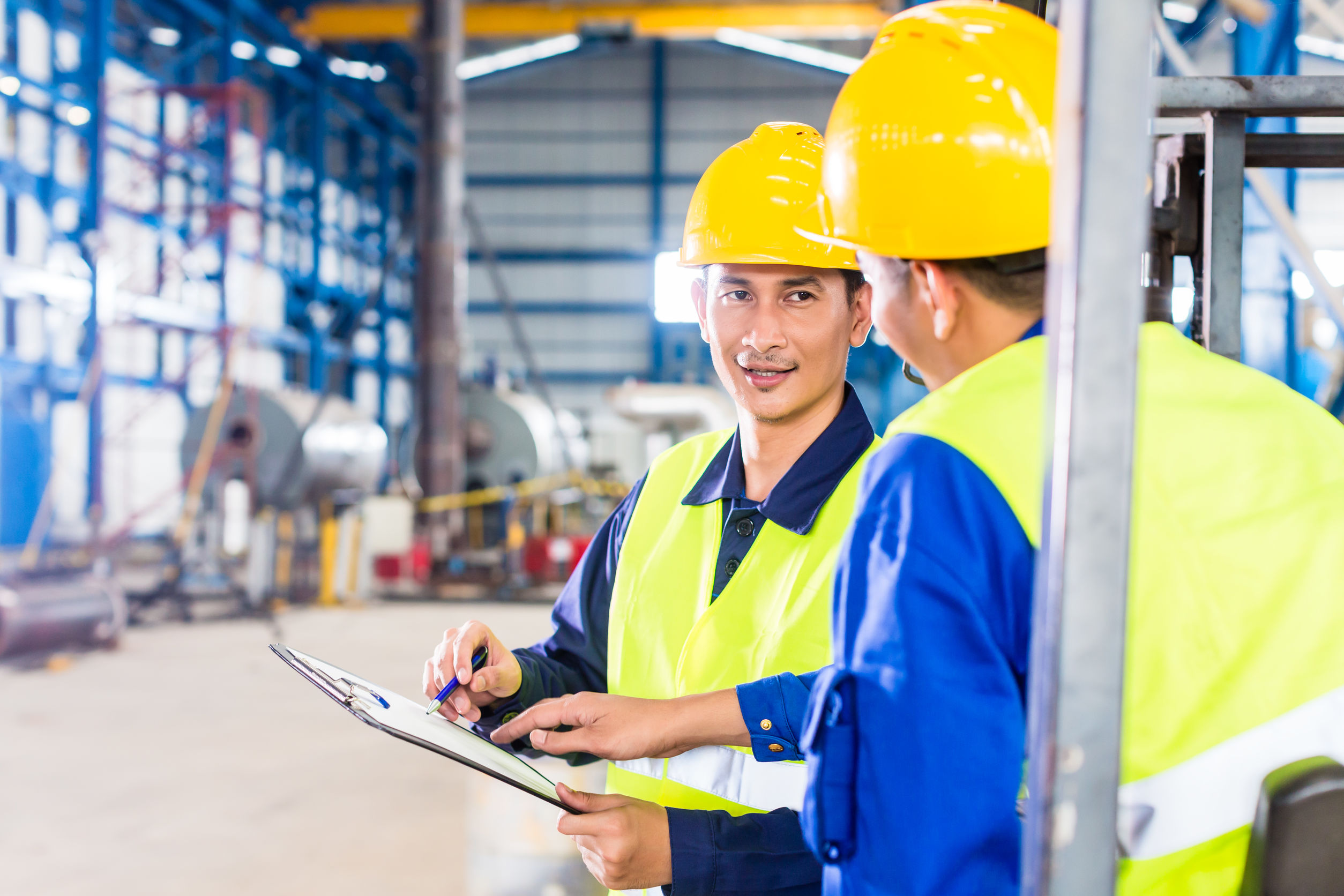 Worker and forklift driver in industrial factory