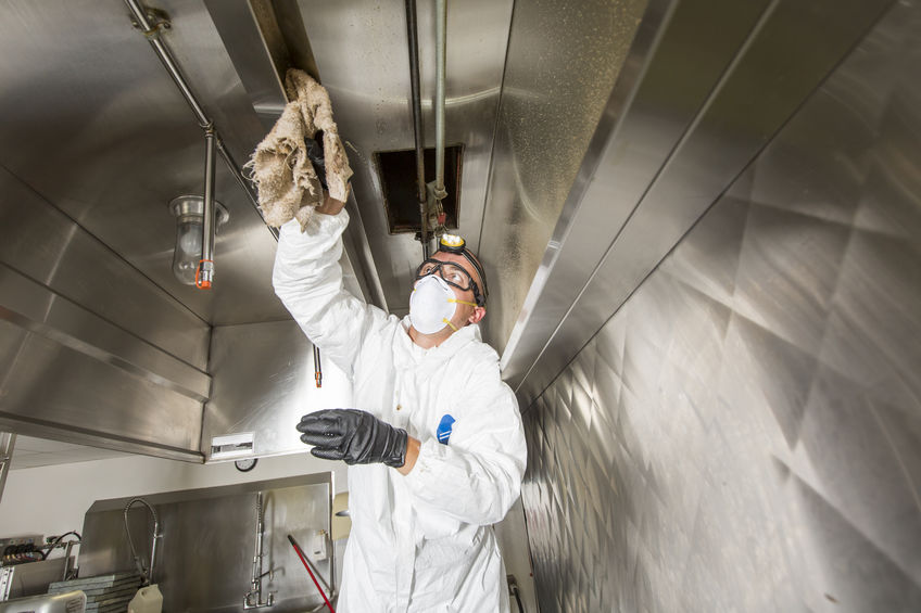 Commercial kitchen worker washing up at sink in professional kitchen